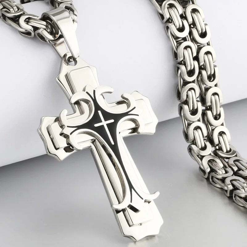 Silver cross pendant on a chain against a light gray background