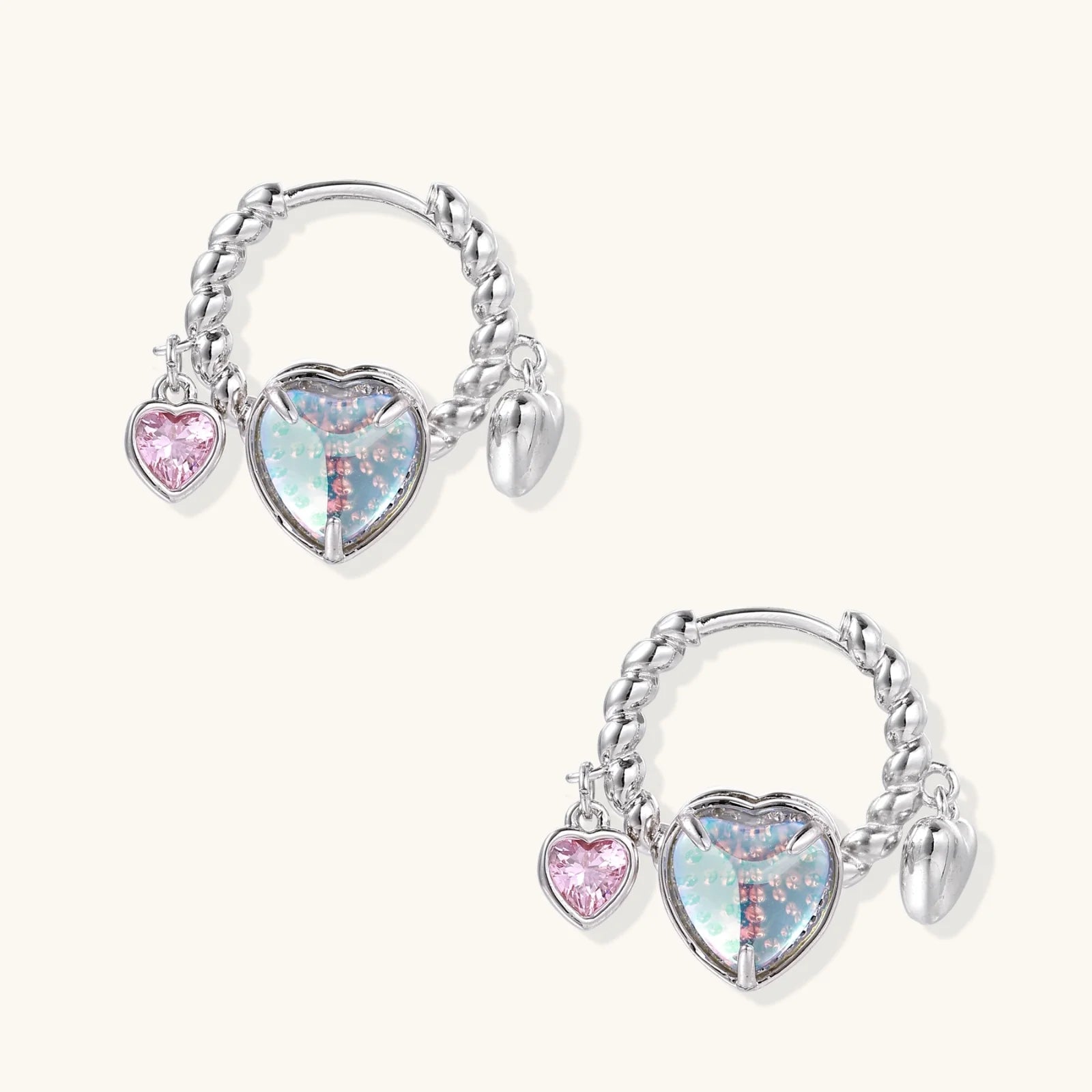 Silver chain hoop earrings with iridescent opal heart charms and pink zirconia accents on white background