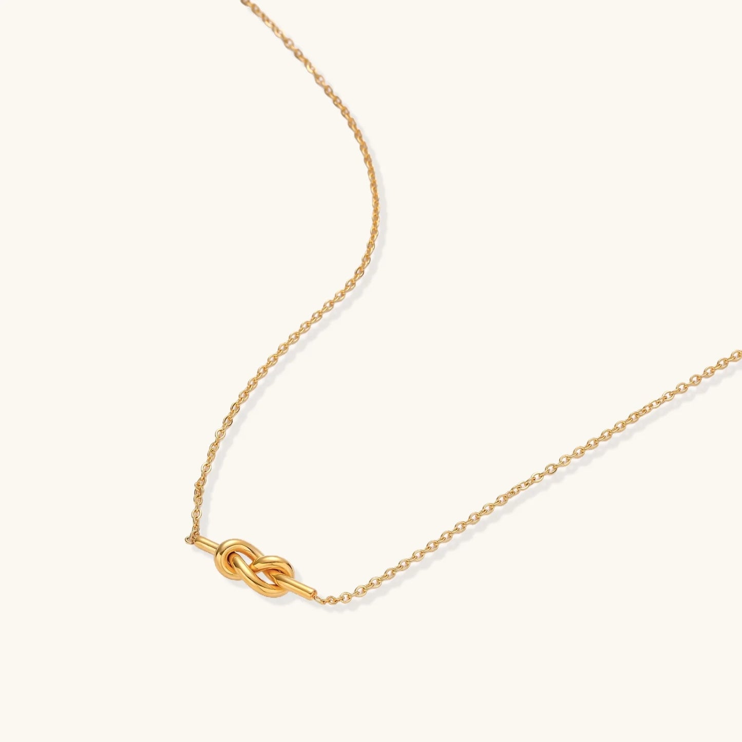 Dainty 18K gold plated necklace with infinity knot pendant on delicate chain against white background
