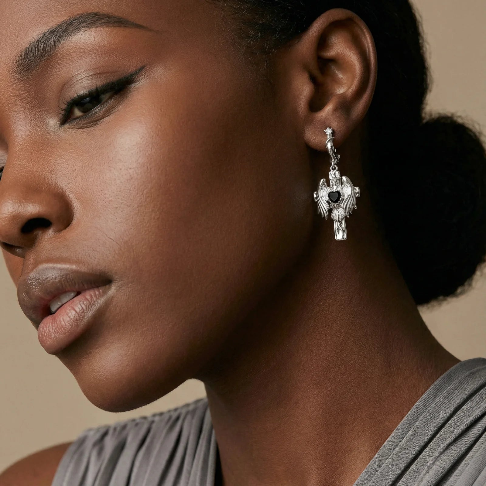 Close-up of a woman wearing a silver earring with a black heart charm.