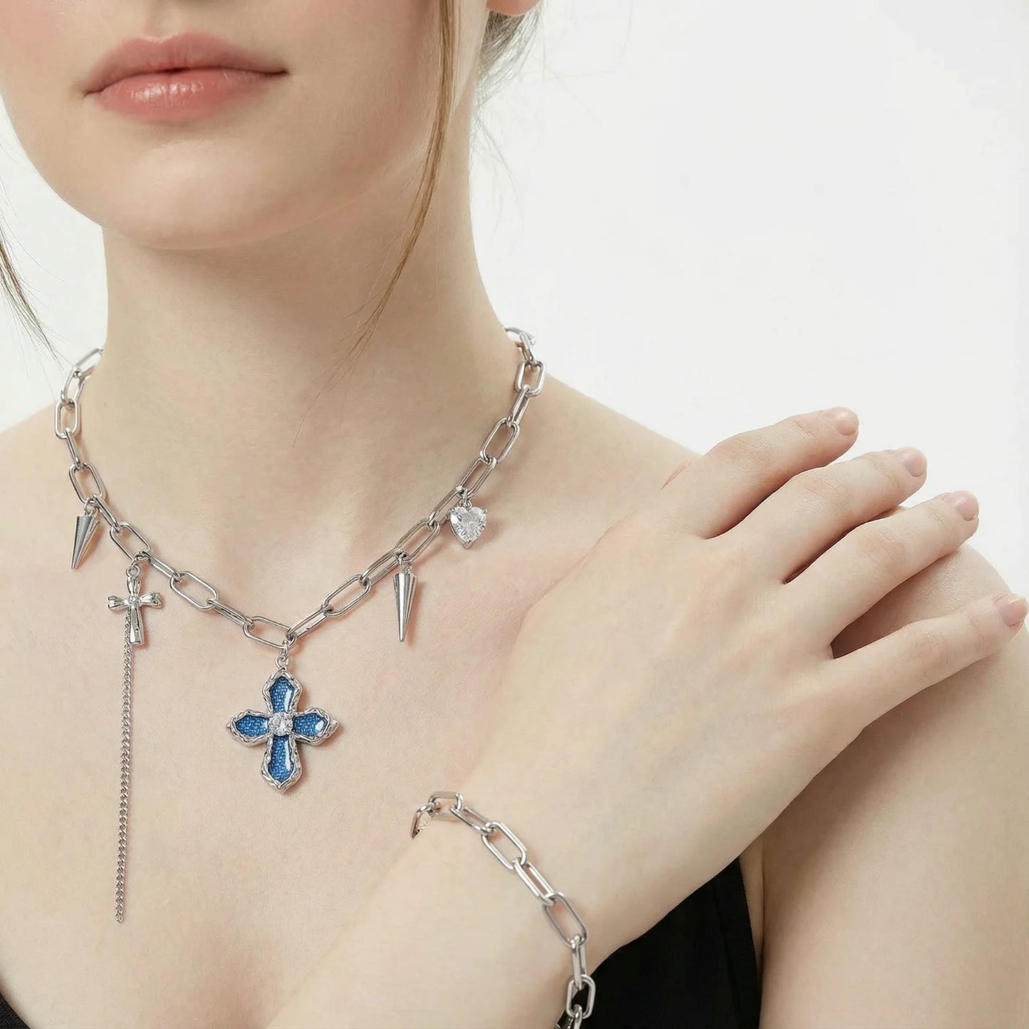 Silver chain necklace with blue flower pendant and matching bracelet on a person against a white background