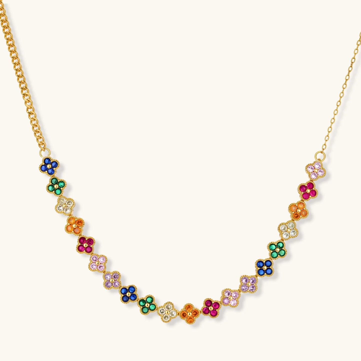 Colorful four-leaf clover jewelry set with rainbow cubic zirconia stones in gold-plated setting on white background