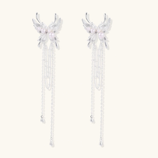 Elegant chandelier earrings with phoenix wing design, white pearls, and cascading silver chains on cream background