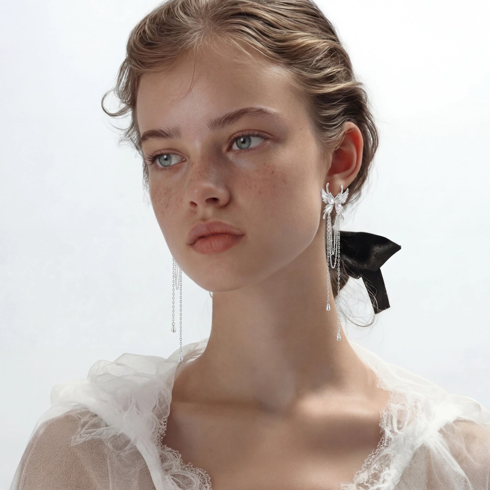 Close-up of a woman wearing elegant earrings with a white lace garment on a light background