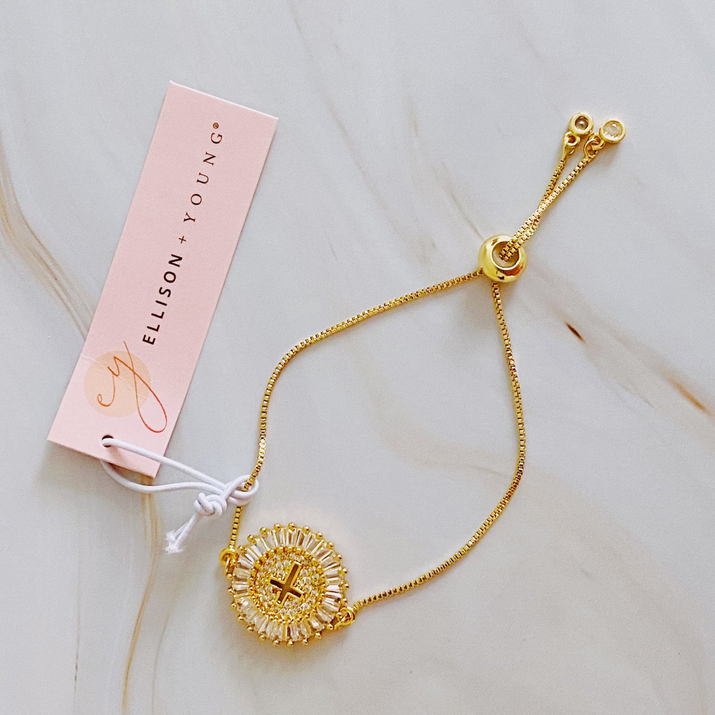 Gold bracelet with intricate design on a light pink card with 'Elison + Young' branding.