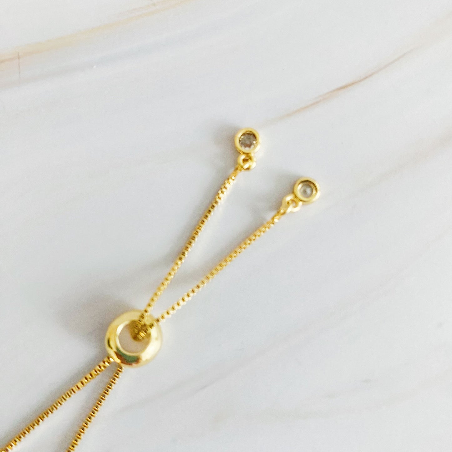 Gold necklace with chain and circular pendants on a light background