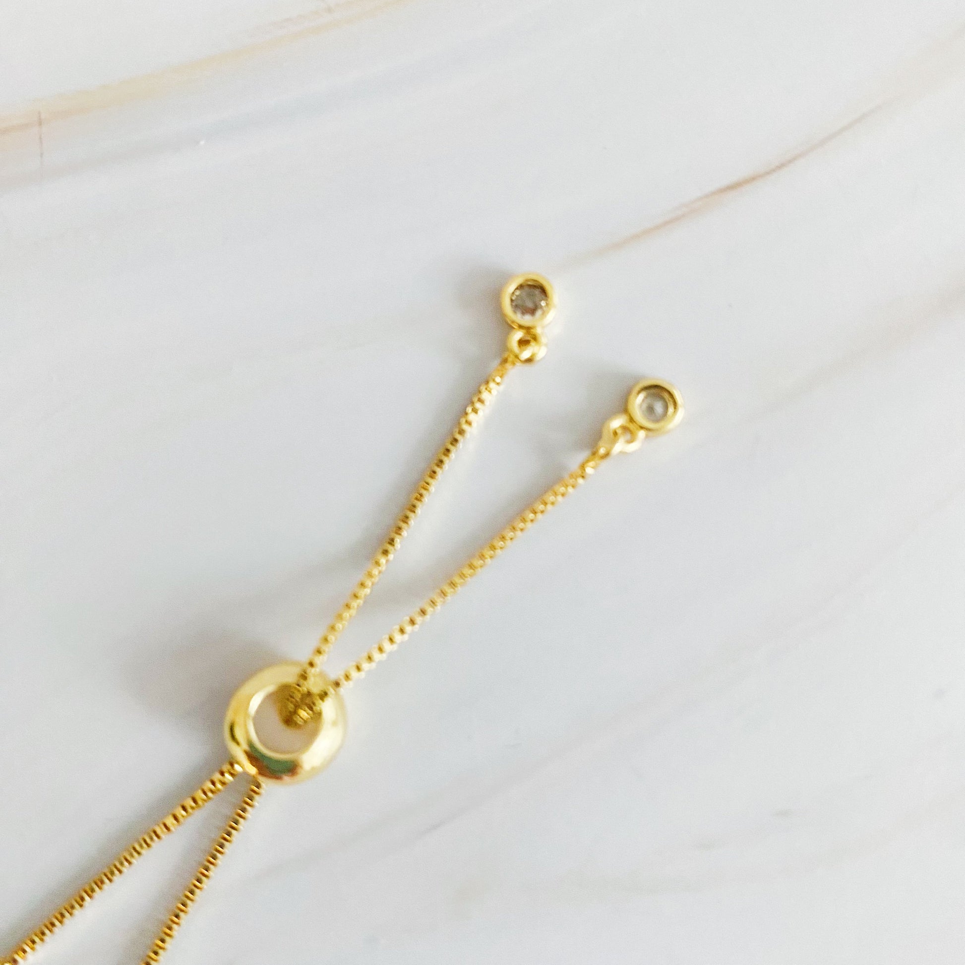 Gold necklace with chain and circular pendants on a light background