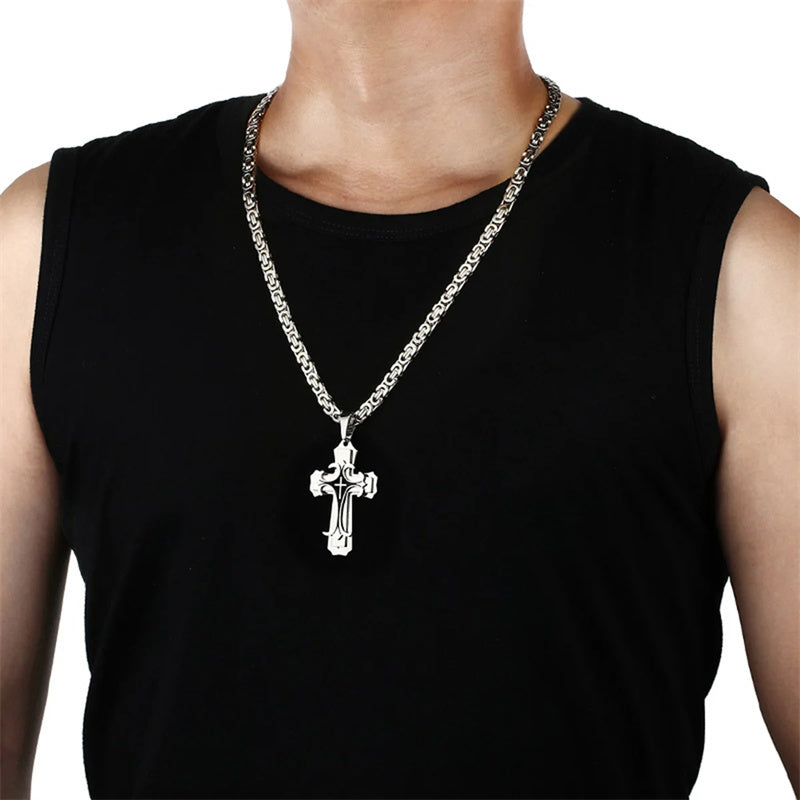 Person wearing a black sleeveless shirt with a silver chain necklace featuring a cross pendant.