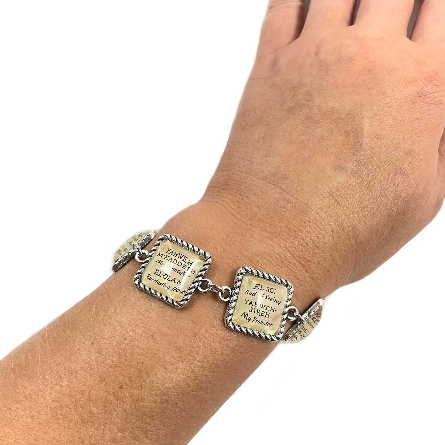 Bracelet with engraved charms on a wrist against a white background
