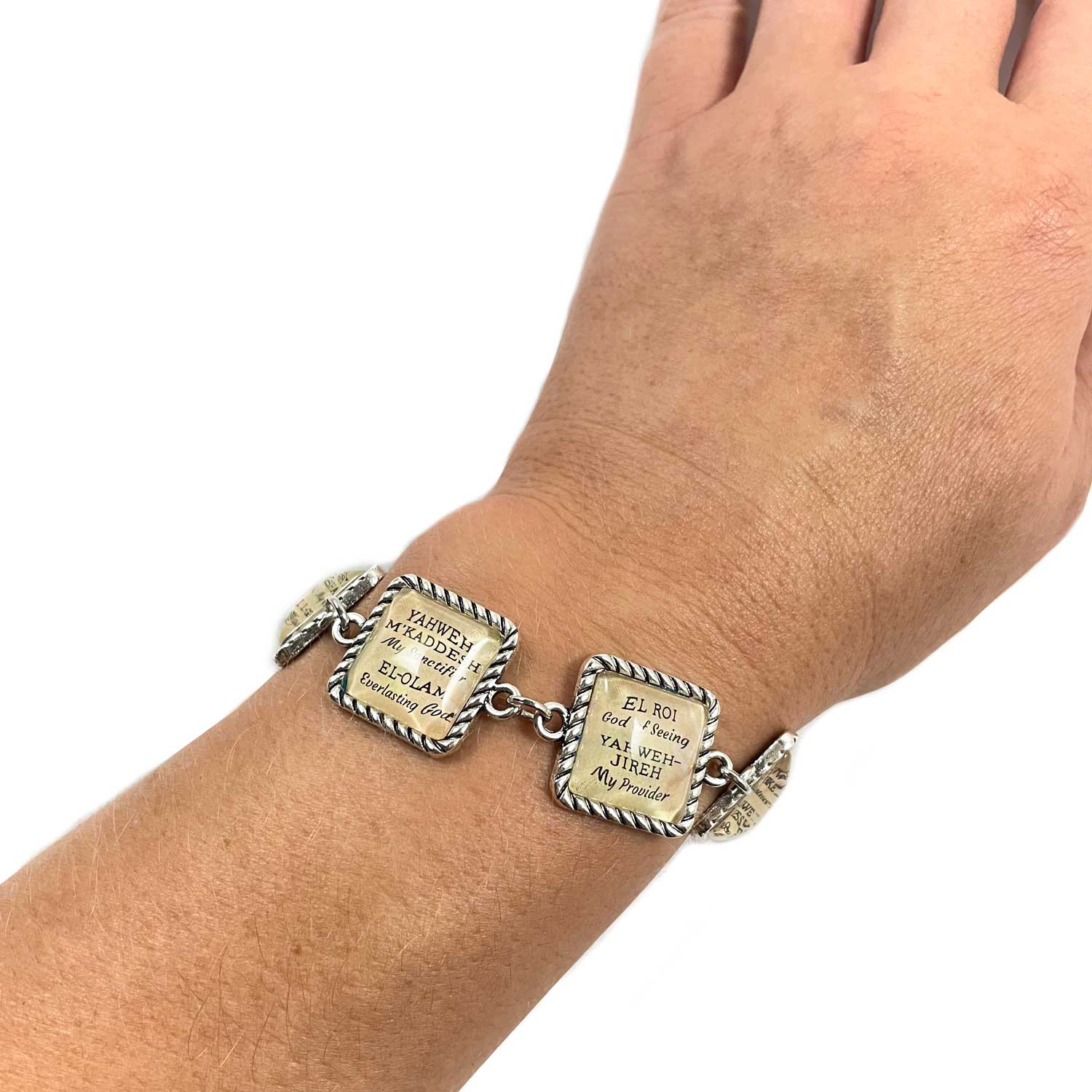 Bracelet with engraved charms on a wrist against a white background