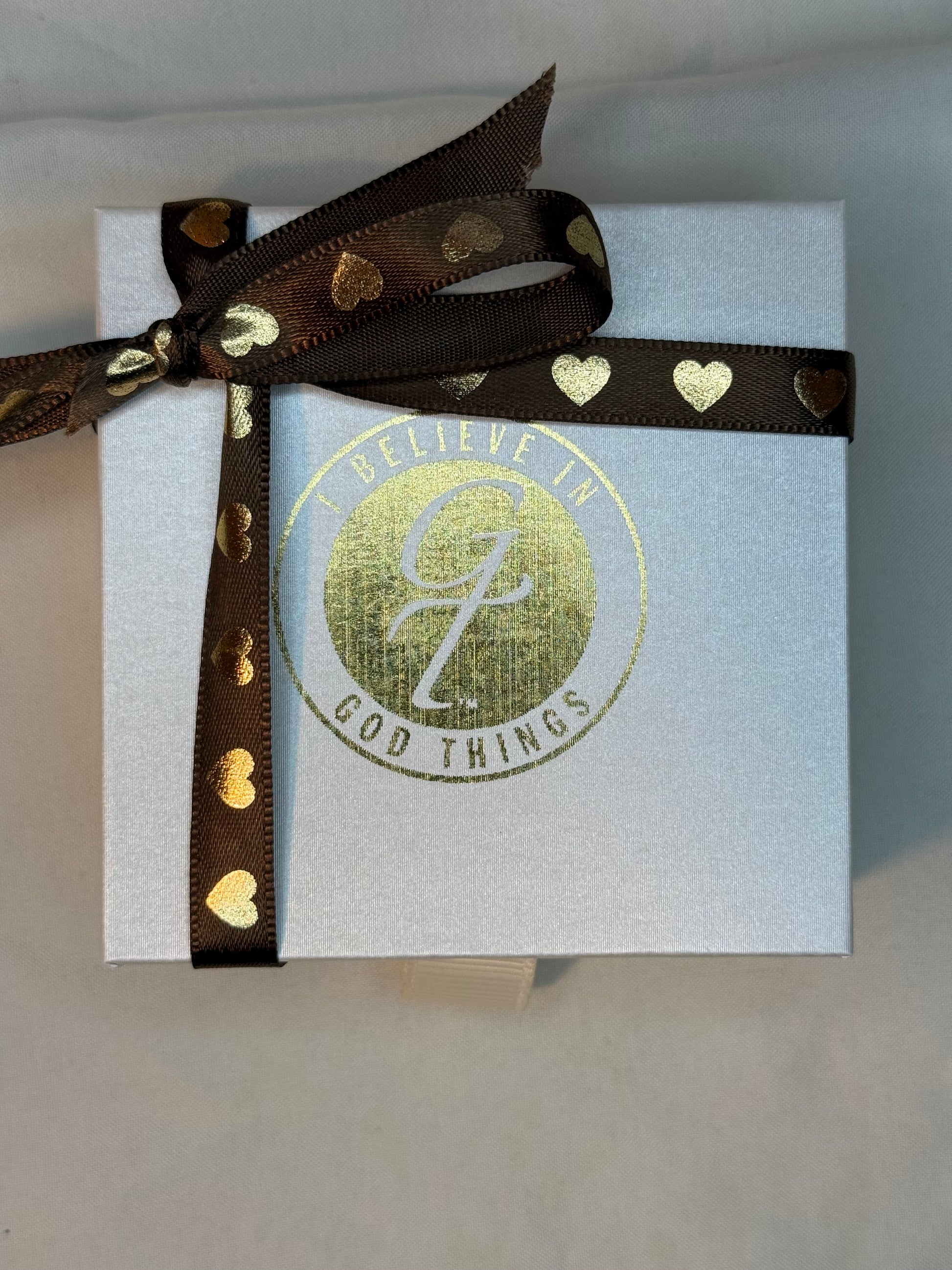 Gift box with a brown ribbon and I Believe In God Things logo
