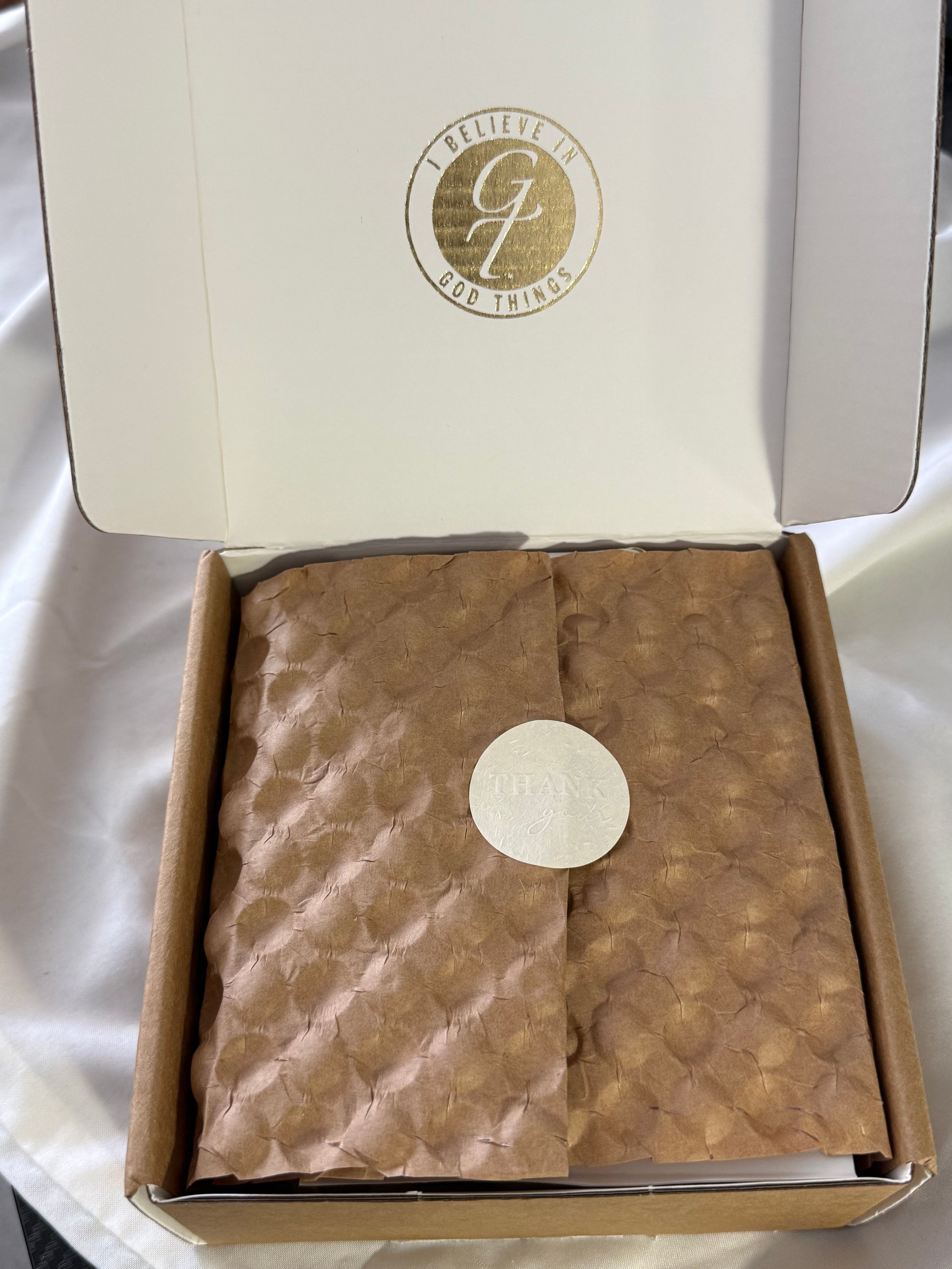 Open box with a brown textured item inside, featuring a visible brand logo on the lid.