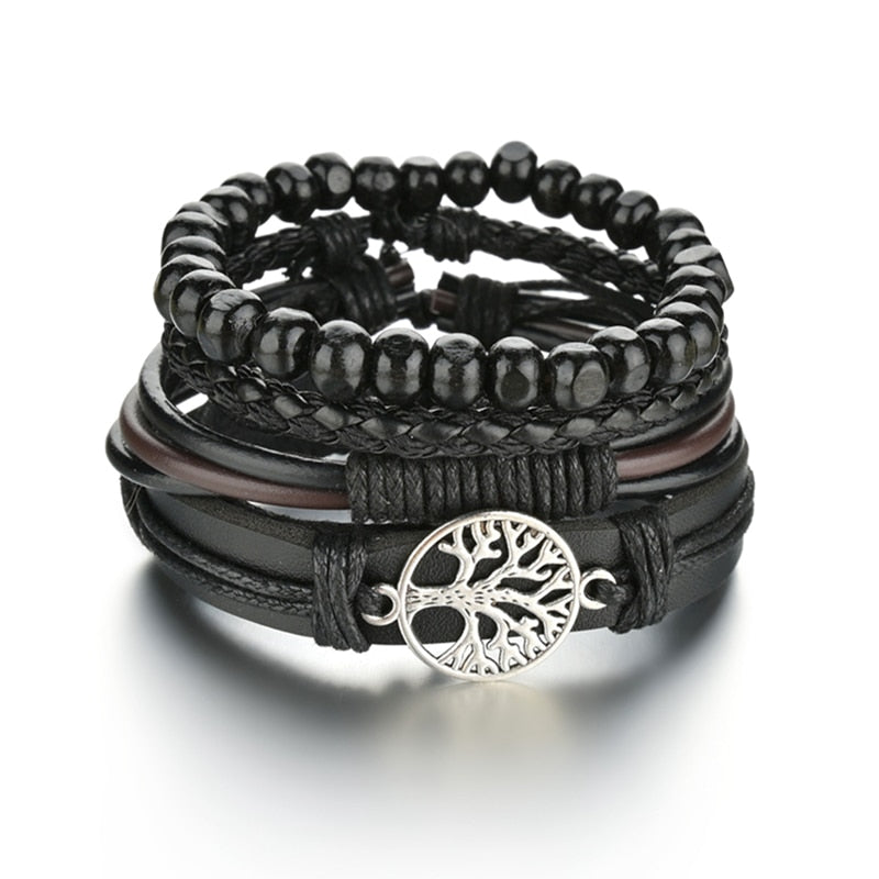 Stack of black beaded and leather bracelets with a tree of life charm on a white background