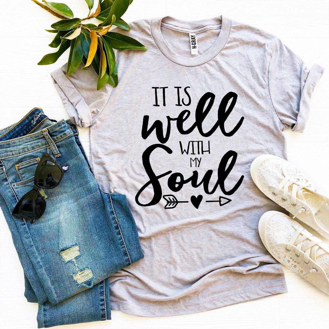 Gray t-shirt with 'It is well with my soul' text, paired with jeans and sneakers on a white background.