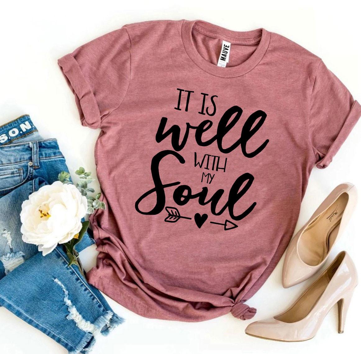 Mauve t-shirt with 'It is well with my soul' text, jeans, and high heels on a white background