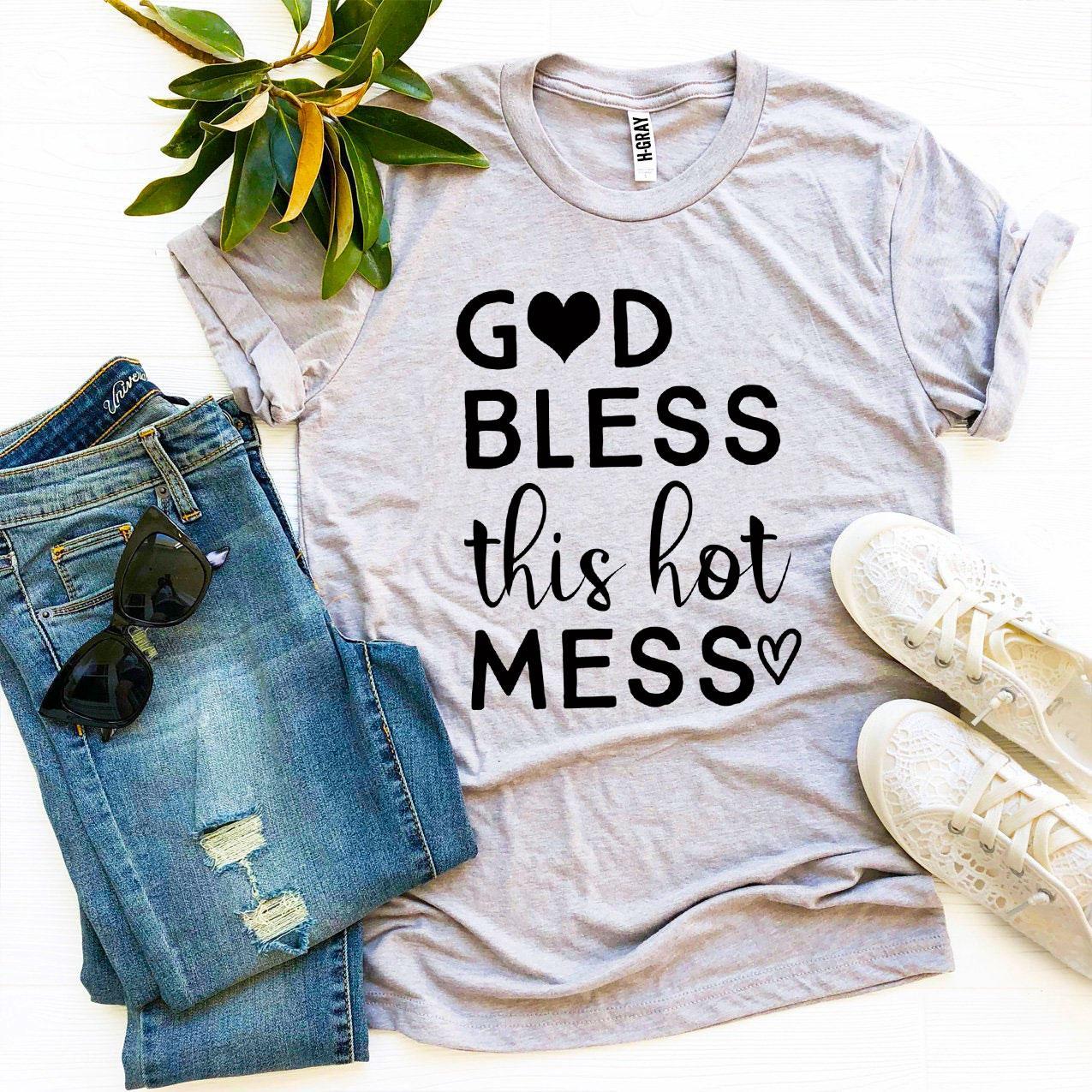 Gray t-shirt with 'God bless this hot mess' text, paired with jeans and sneakers on a light background
