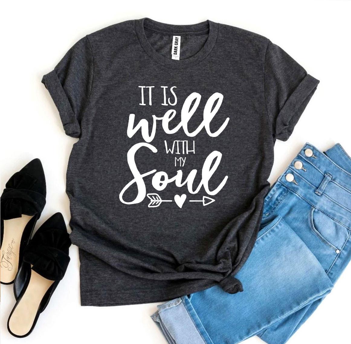 Dark gray t-shirt with 'It is well with my soul' text, paired with jeans and shoes on a white background