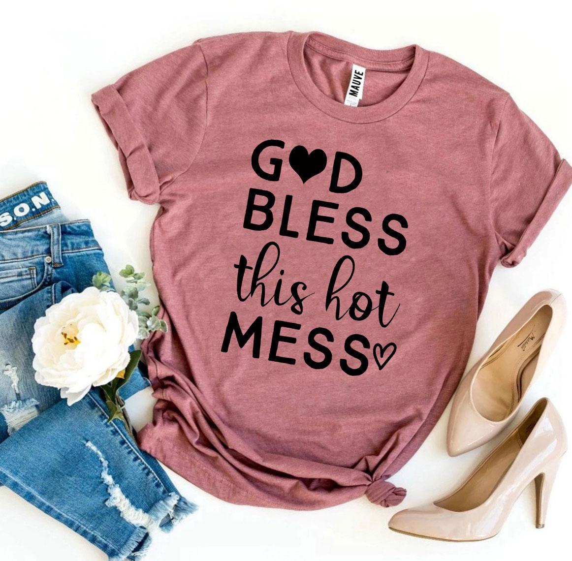 Mauve t-shirt with 'God bless this hot mess' text, paired with jeans and high heels on a white background