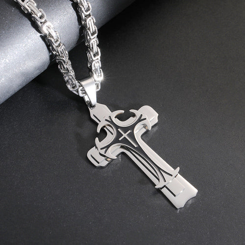 Silver cross pendant necklace on a dark surface
