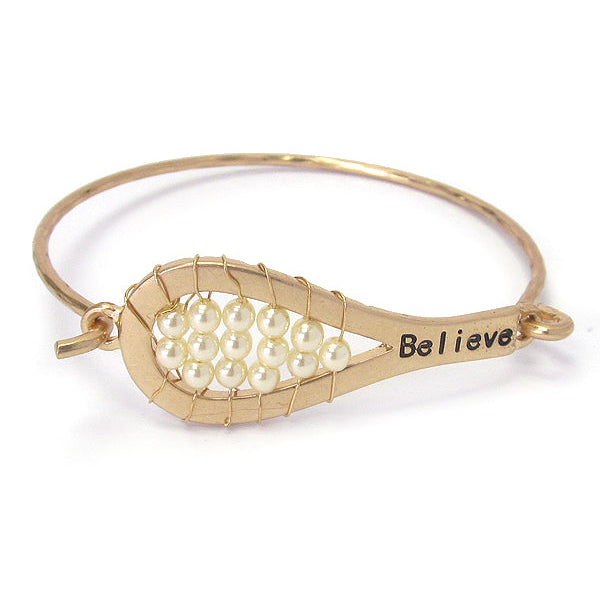 Gold bracelet with pearl beads and 'Believe' engraving on a white background