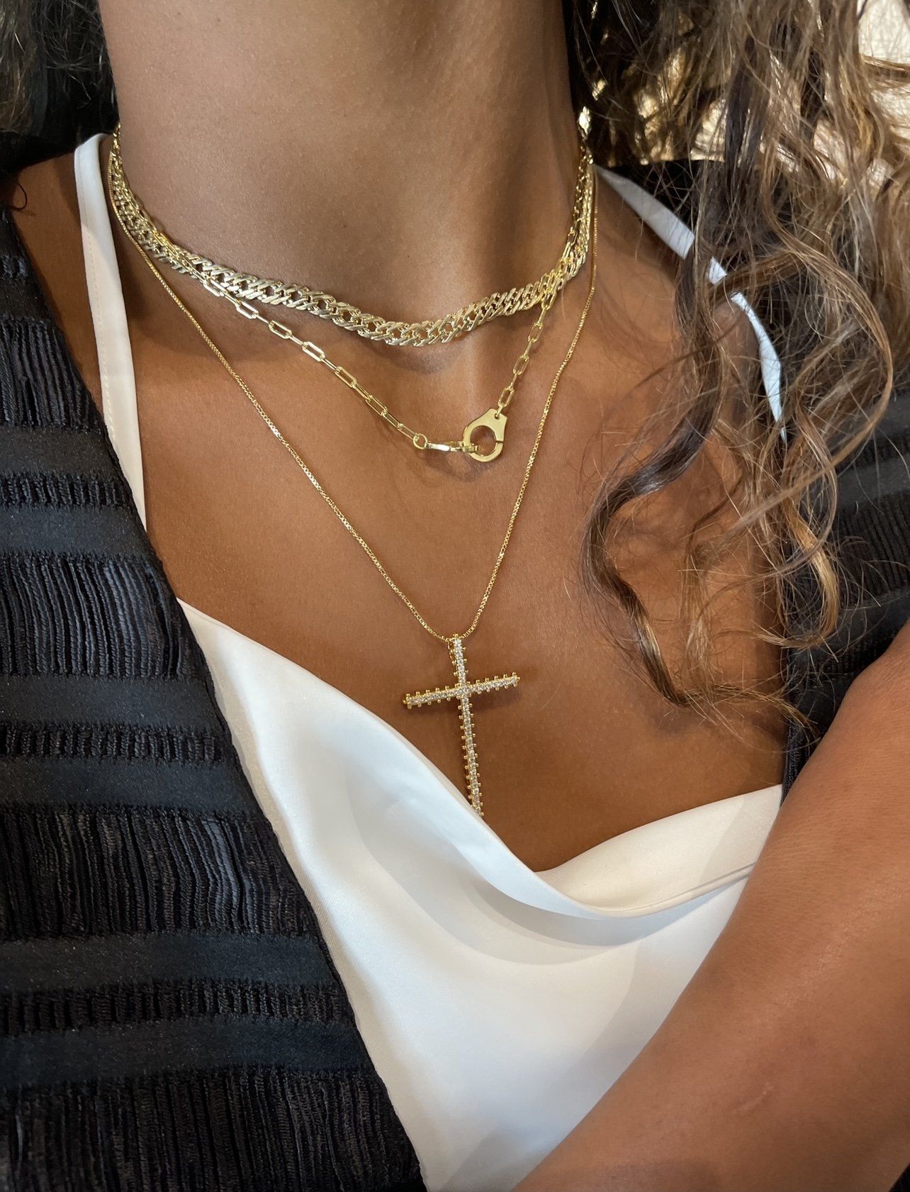 Close-up of a person wearing gold necklaces with a cross pendant.